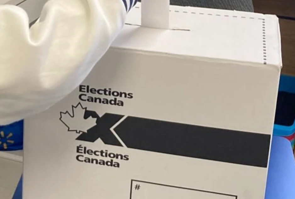 Boîte récipiente des bulletins de vote d'Élections Canada, la main d'un élève qui y met son bulletin de vote replié